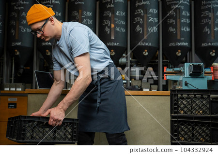 Caucasian man coffee shop worker gets new batch of coffee packages in boxes on roasting factory. 104332924