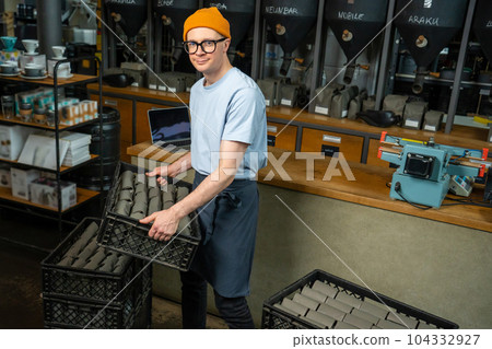 Bartender barista uploads paper coffee packages in boxes on roasting factory or coffee shop. Bartender barista uploads paper coffee packages in boxes on roasting factory or coffee shop. 104332927