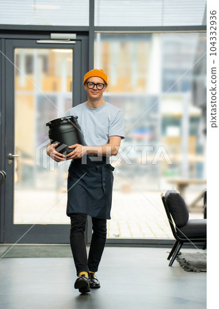 Barista carrying barrel preparing for work in coffee shop. 104332936