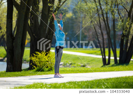 Woman standing on the park road with her arms up 104333040