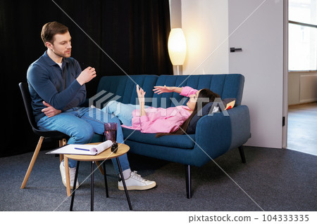 Attractive woman reclining comfortably on a couch talking to his psychiatrist explaining something 104333335