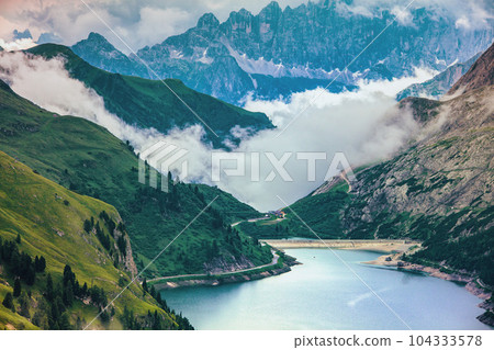 landscape with mountains, hills, Fedaia lake, trees and fog landscape with mountains, hills, Fedaia lake, trees and fog 104333578