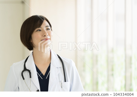 A female medical worker in a white coat A female medical worker in a white coat 104334004