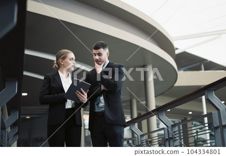 Young business couple discussing and using tablet to discuss work outside the office Young business couple discussing and using tablet to discuss work outside the office 104334801