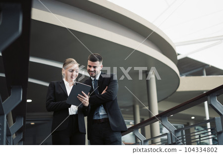 Young business couple smiling and using tablet talking about work 104334802