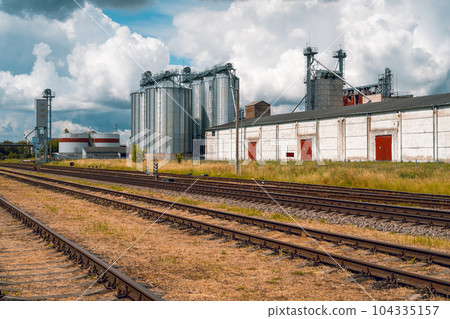 A railroad tracks passing near big steel silos 104335157