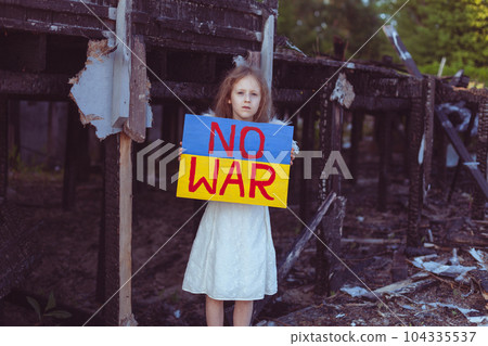 A girl in front of a destroyed, burned-out house. 104335537
