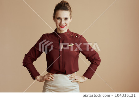 Portrait of happy stylish flight attendant woman on beige 104336121