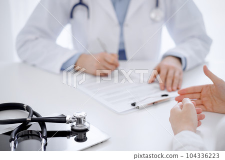 Stethoscope lying on the tablet computer in front of a doctor and patient sitting opposite each other at the background . Medicine, healthcare concept Stethoscope lying on the tablet computer in front of a doctor and patient sitting opposite each other at the background . Medicine, healthcare concept 104336223