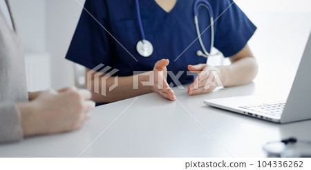 Doctor and patient talking to each other during current health examination while sitting at the desk in clinic, closeup of hand. Perfect medical service and medicine concept 104336262