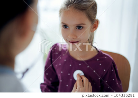 Happy smiling child girl patient at usual medical inspection. Doctor and kid patient at home. Medicine, healthcare concepts 104336291