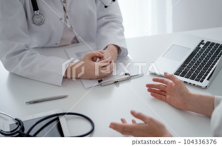 Doctor and patient discussing current health questions while sitting at the desk in clinic office, closeup. Medicine and healthcare concept Doctor and patient discussing current health questions while sitting at the desk in clinic office, closeup. Medicine and healthcare concept 104336376