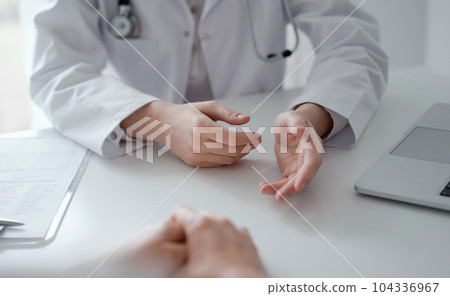 Doctor and patient discussing current health examination while sitting at the desk in clinic office, closeup. Medicine concept 104336967