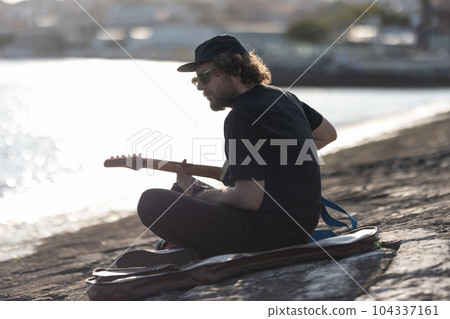 A man hipster playing guitar at the quay 104337161