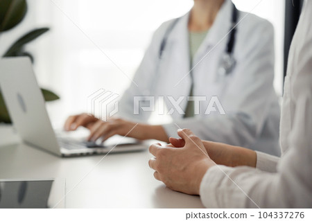 Doctor and patient discussing current health examination while sitting at the desk in clinic office, closeup. Perfect medical service and medicine concept 104337276
