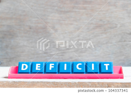 Tile alphabet letter with word deficit in red color rack on wood background Tile alphabet letter with word deficit in red color rack on wood background 104337341
