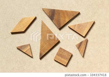 Straggled tangram puzzle  wait to complete the shape on wood background 104337418
