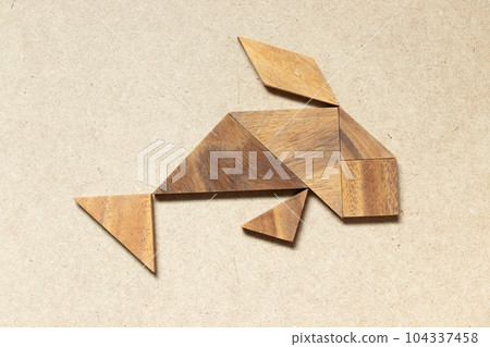 Wooden tangram in swimming fish or carp shape on wood background Wooden tangram in swimming fish or carp shape on wood background 104337458