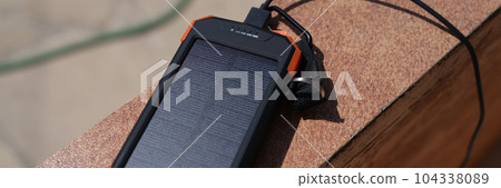 Solar charger lying outside and charging under sun rays closeup Solar charger lying outside and charging under sun rays closeup 104338089