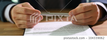 Businessman in suit holding ballpoint pen over document and thinking about signing closeup 104339062
