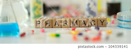 Pharmacy word on wooden cubes near many medicines 104339141