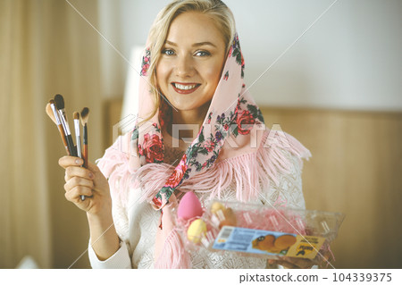 Smiling caucasian woman holding a basket with colorful Easter eggs 104339375