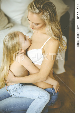 Happy mom and little daughter cuddle while dressing. Motherhood and family concept Happy mom and little daughter cuddle while dressing. Motherhood and family concept 104339378
