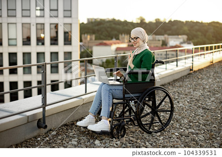 Muslim lady in wheelchair holding web conference via laptop Muslim lady in wheelchair holding web conference via laptop 104339531
