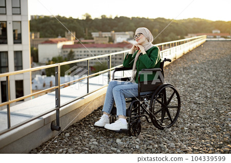 Muslim female with mobility issues daydreaming on terrace Muslim female with mobility issues daydreaming on terrace 104339599