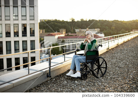 Muslim female with mobility issues daydreaming on terrace 104339600