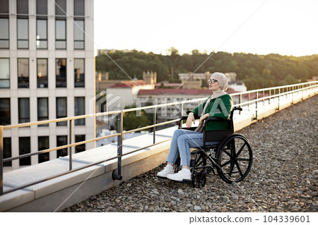Muslim female with mobility issues daydreaming on terrace Muslim female with mobility issues daydreaming on terrace 104339601