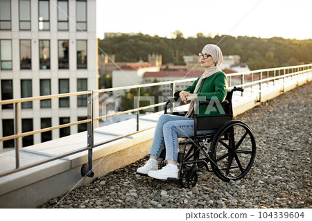 Arabian lady with mobility impairment posing on terrace 104339604