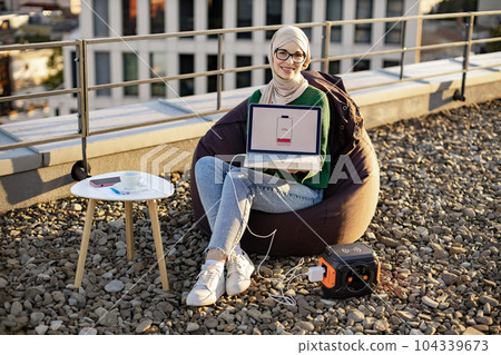 Female showing discharged laptop plugged into power station 104339673