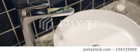 White sink and metal faucet in bathroom closeup White sink and metal faucet in bathroom closeup 104339989