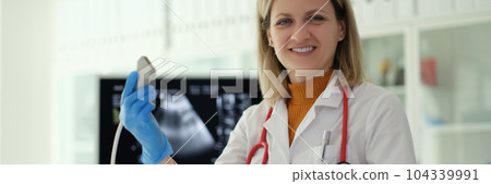 Smiling woman doctor holding ultrasound probe in hands to diagnose early pregnancy in clinic Smiling woman doctor holding ultrasound probe in hands to diagnose early pregnancy in clinic 104339991