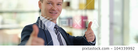 Happy smiling businessman showing thumbs up gesture in office Happy smiling businessman showing thumbs up gesture in office 104339992