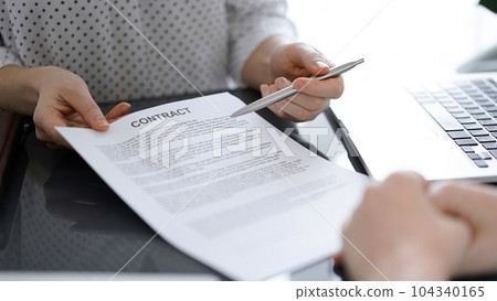 Business people sitting and discussing contract in office, closeup. Partners or lawyers working together at meeting before signing papers. Teamwork and partnership Business people sitting and discussing contract in office, closeup. Partners or lawyers working together at meeting before signing papers. Teamwork and partnership 104340165