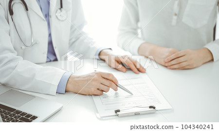 Doctor and patient discussing current health questions while sitting near of each other and using clipboard at the table in clinic, just hands closeup. Medicine concept 104340241