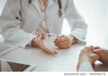 Doctor and patient discussing current health questions while sitting at the desk in clinic office, closeup. Medicine and healthcare concept 104340274