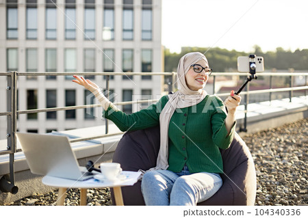 Female blogger recording video on phone via stick outdoors Female blogger recording video on phone via stick outdoors 104340336