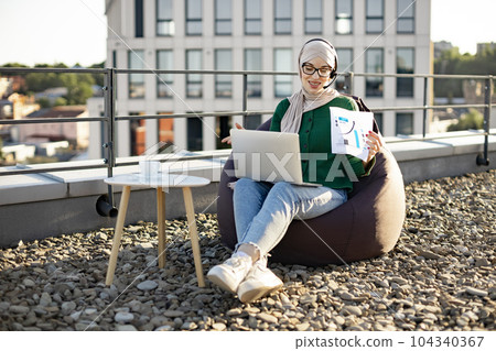 Adult in scarf presenting data online via gadgets outdoors 104340367