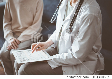 Doctor woman and kid boy patient at home. The pediatrician using tablet computer while filling up medical records, close up. Medicine, healthcare concept 104340634