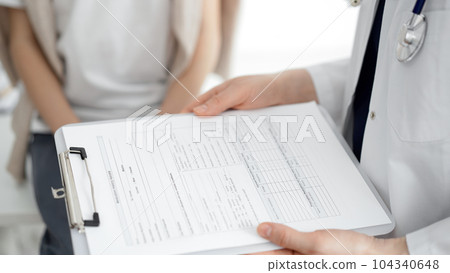 Doctor and child patient. The physician is holding clipboard with medication history records form near a boy. The concept of ideal health in medicine Doctor and child patient. The physician is holding clipboard with medication history records form near a boy. The concept of ideal health in medicine 104340648