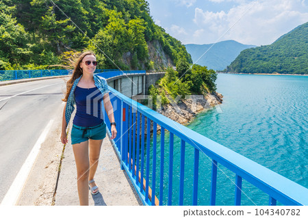 Young woman walking on the bridge across Piva lake in Montenegro 104340782