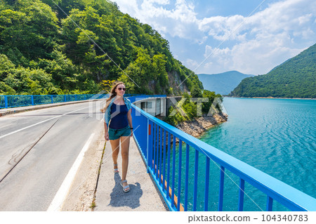 Young woman walking on the bridge across Piva lake in Montenegro 104340783