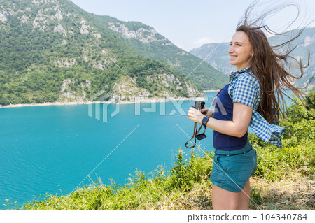 Young woman using binoculars exploring the nature at the Piva lake in Montenegro Young woman using binoculars exploring the nature at the Piva lake in Montenegro 104340784