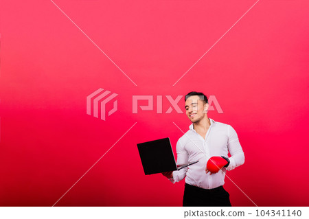 Guy in boxing gloves and formalwear punch computer isolated on red, cyber bullying. 104341140