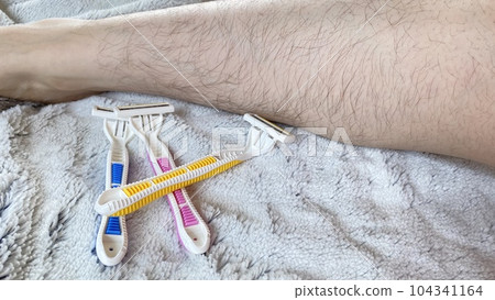 Pink, yellow and blue disposable razors and hairy female legs Pink, yellow and blue disposable razors and hairy female legs 104341164