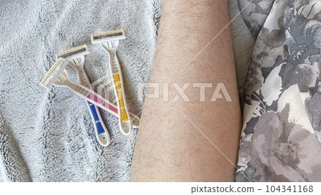 粉色、黃色和藍色一次性剃須刀和毛茸茸的女性腿 104341168
