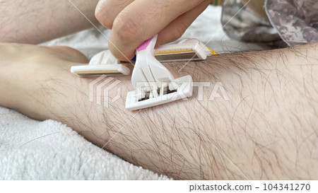 女性用粉色和黃色一次性剃須刀自清潔多餘頭髮的特寫 104341270
